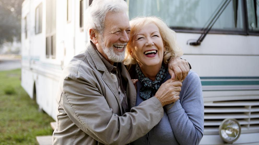 A happy elderly couple embracing outside of their RV.